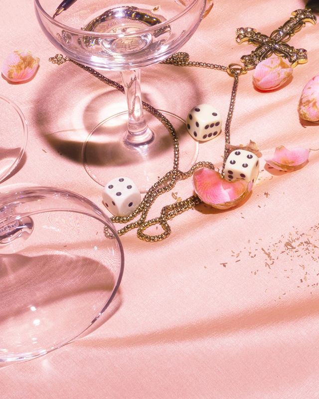 Glass, terninger og roseblader på rosa duk
